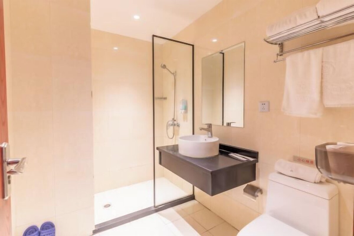 Un baño moderno con cabina de ducha de vidrio, un lavamanos blanco y un perchero para toallas.