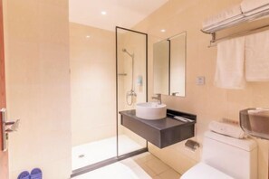 Un baño moderno con cabina de ducha de vidrio, un lavamanos blanco y un perchero para toallas.