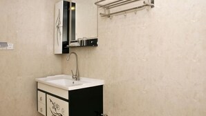 Un baño con lavamanos, espejo, toallero y armario.