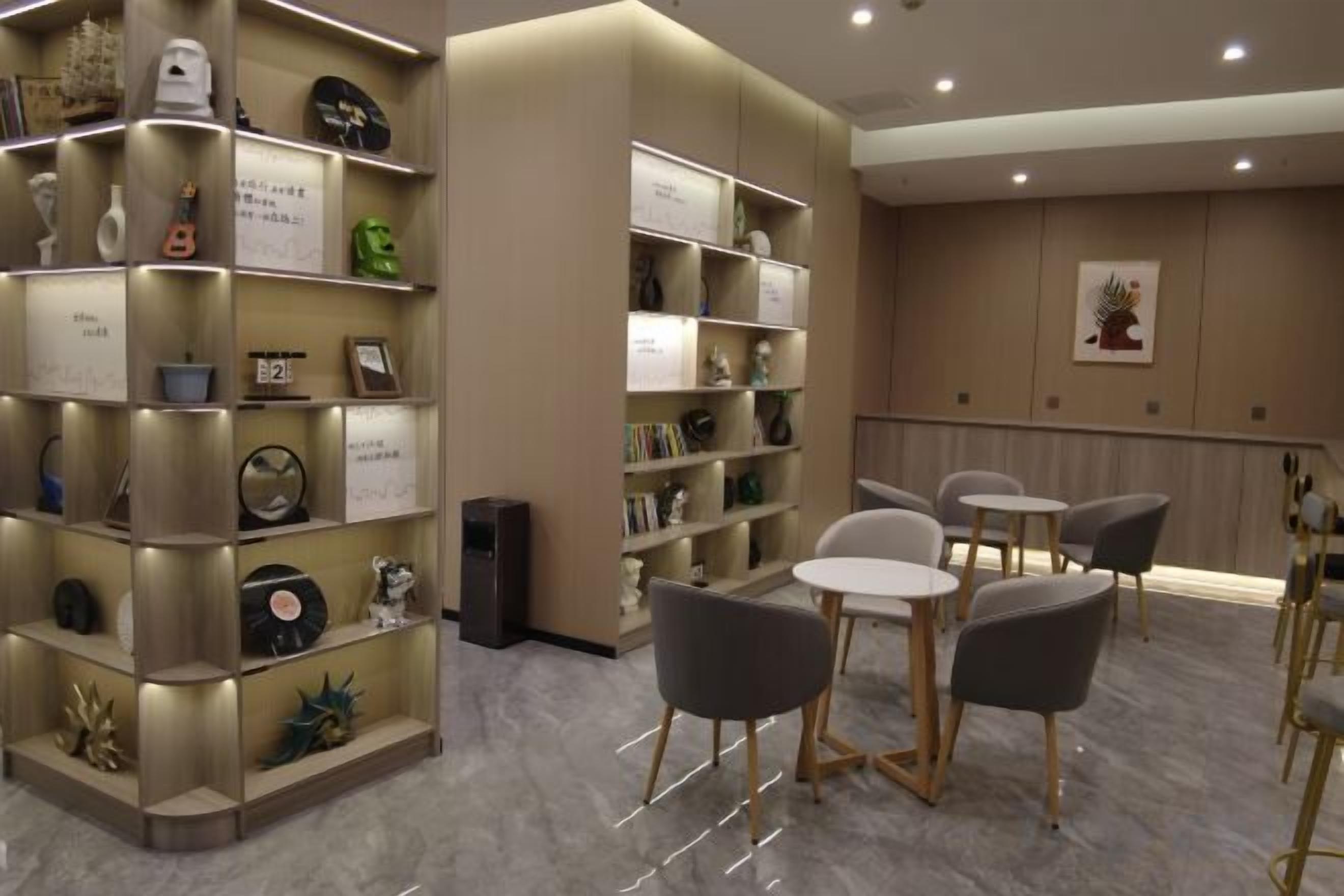 Una hall d'albergo con un'area salotto, scaffali di libri e una parete decorativa.