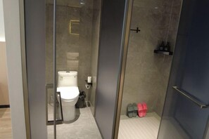 A modern bathroom with a glass partition, a toilet, a shower area, and a pair of slippers. - Tumed Zuoqi Zhejiang Jiadu Business Hotel (Tumed Left Banner)