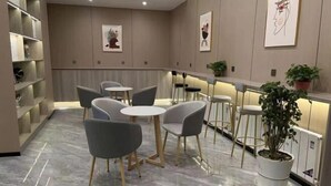 Ein stilvoller Lounge-Bereich mit Marmorboden, grauen Polstermöbeln und einer weißen Bar mit Topfpflanzen.