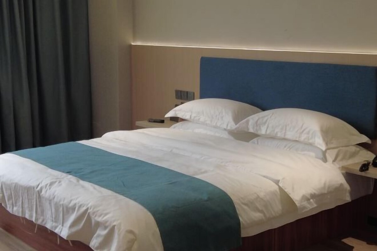 A hotel room with a bed, a nightstand, and a blue headboard.