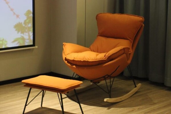 A room with a rocking chair and ottoman, a projector screen, and a window with curtains. - Tumed Zuoqi Zhejiang Jiadu Business Hotel (Tumed Left Banner)