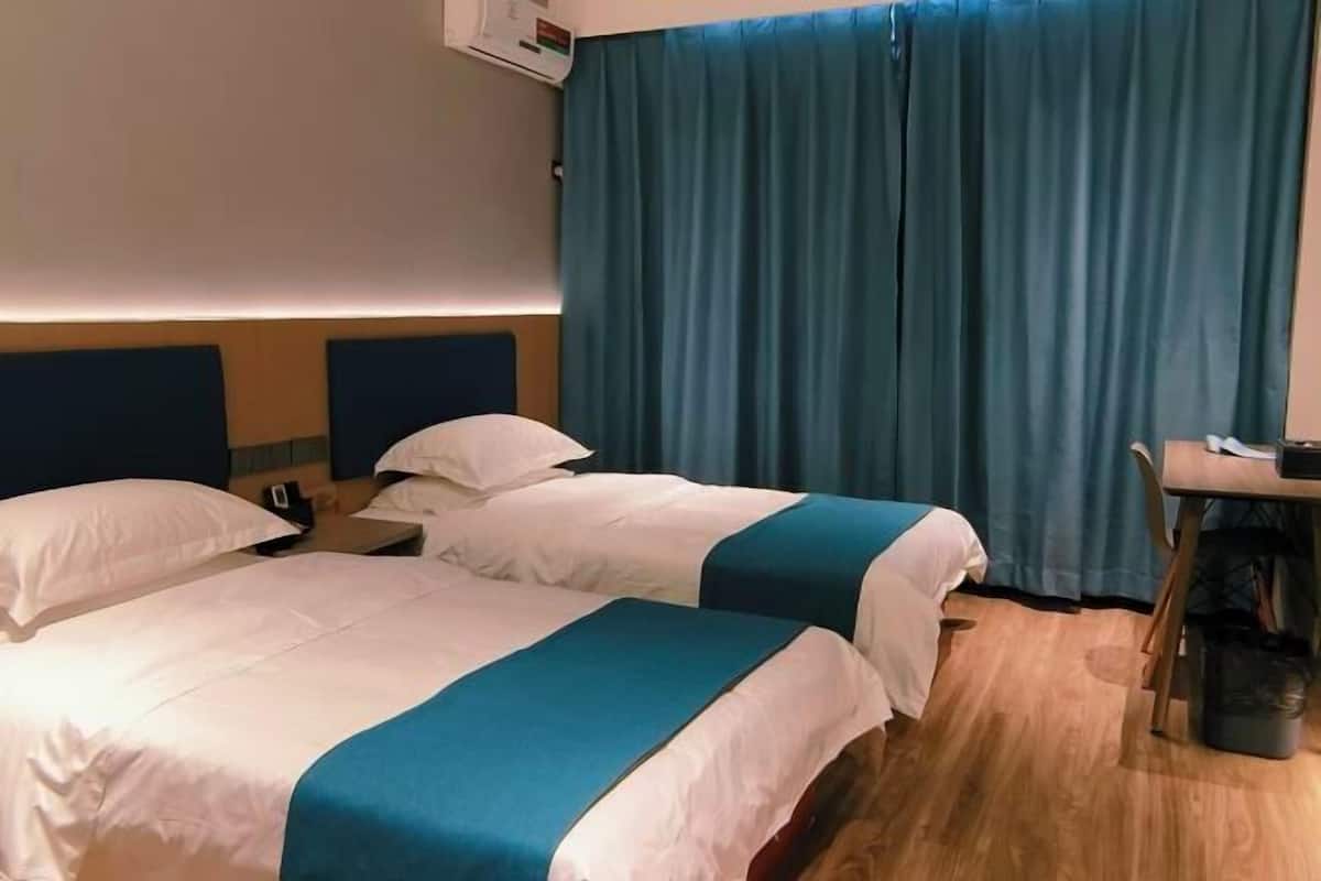 A hotel room with two beds, a desk, and a chair.