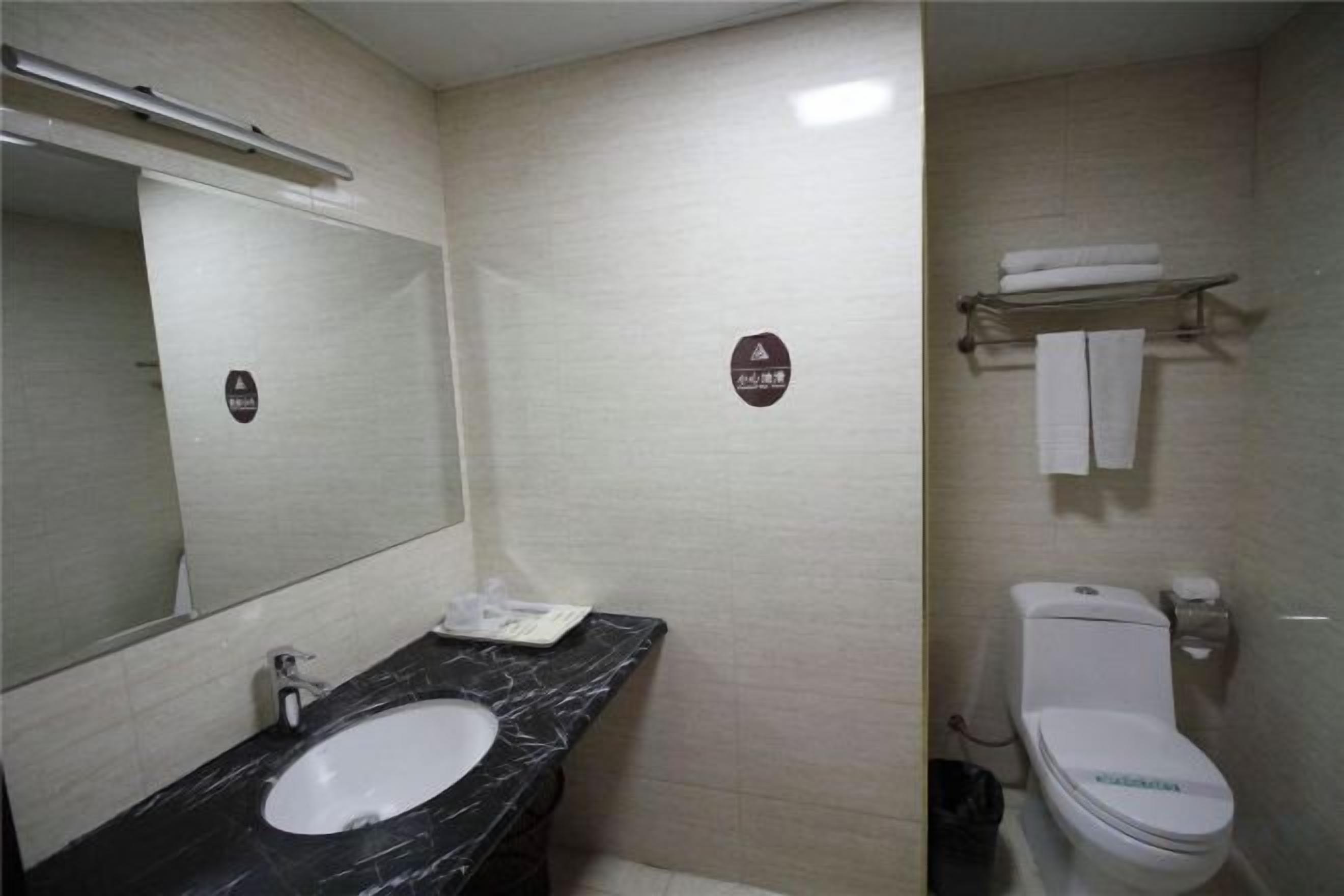 Un baño con lavamanos, espejo, inodoro y toallero.