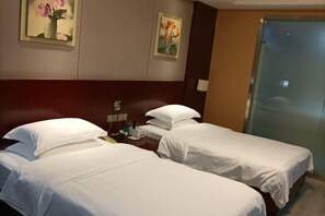 A hotel room with two single beds, a wooden headboard, a small table with a lamp, and two paintings on the wall. - Fuqing New Port Express Hotel (Fuqing)