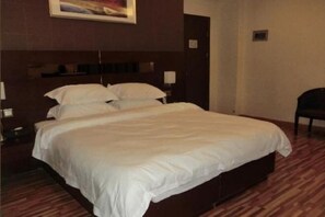 A hotel room with a large bed, a wooden headboard, a nightstand, and a chair. - Fuqing New Port Express Hotel (Fuqing)
