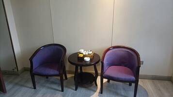 Two purple upholstered chairs, a small round table with a tea set, and a plain wall with a door on the left.