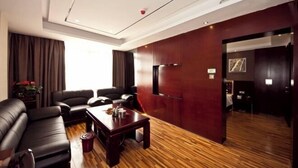 A modern living room with leather sofas, a wooden coffee table, and a red accent wall. - Fuqing New Port Express Hotel (Fuqing)