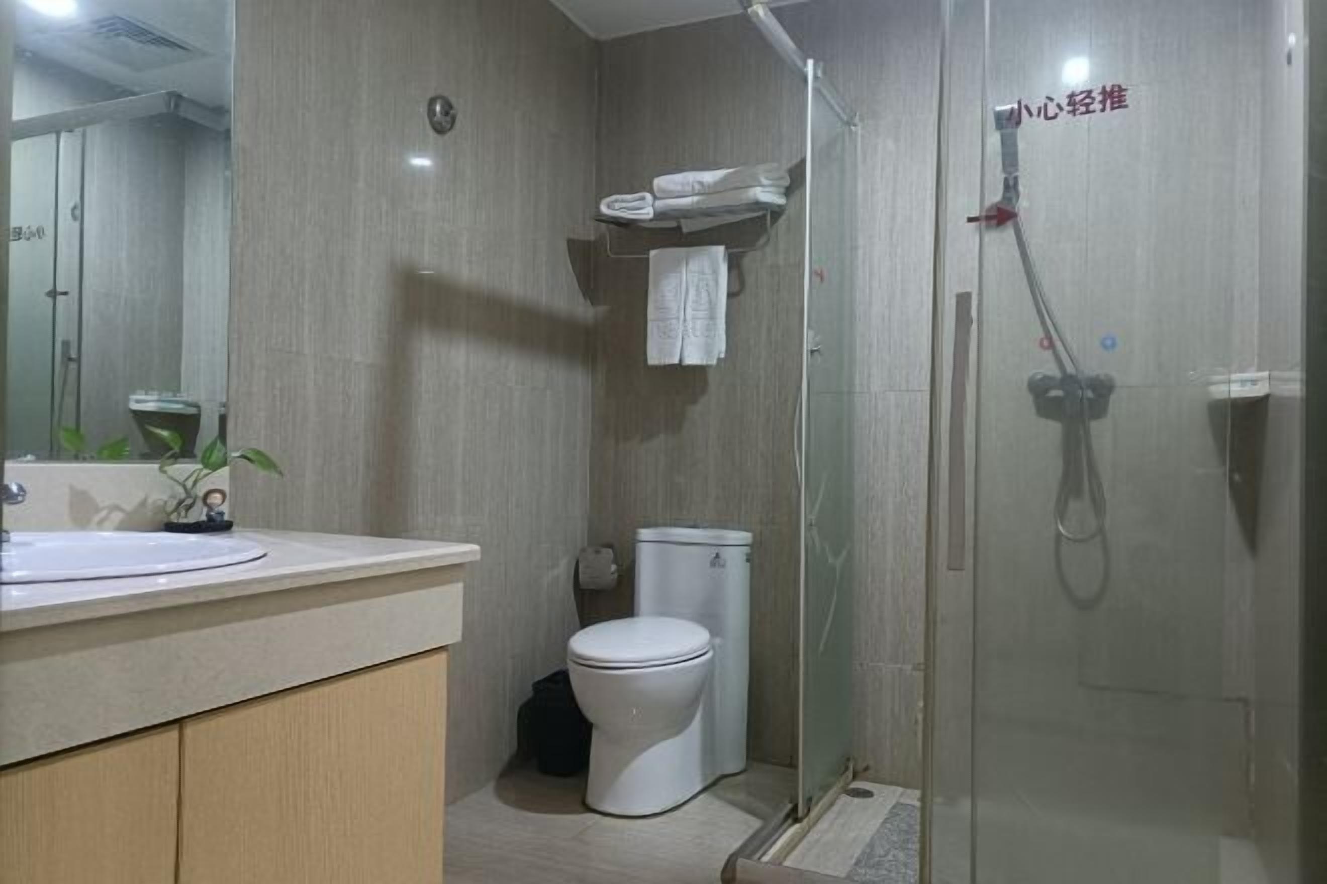A modern bathroom with a toilet, sink, and glass shower enclosure.