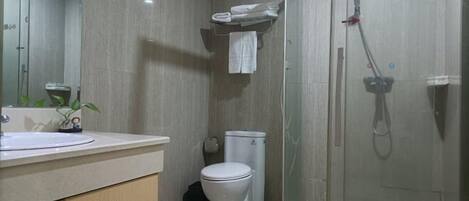 Un baño moderno con inodoro, lavamanos y cabina de ducha de vidrio.