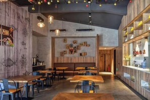 Een restaurantinterieur met houten tafels en stoelen, een bar en wanddecoraties.
