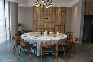 Ein runder Esstisch mit Stühlen, eine Chandelüster und eine Wand mit Holzverkleidung.