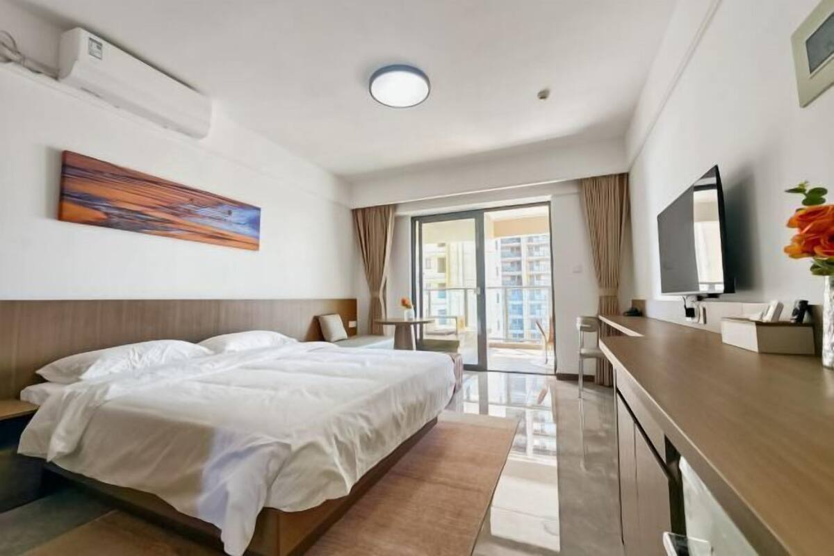 Une chambre d’hôtel avec un lit, un bureau, une télévision et une vue sur les bâtiments environnants.