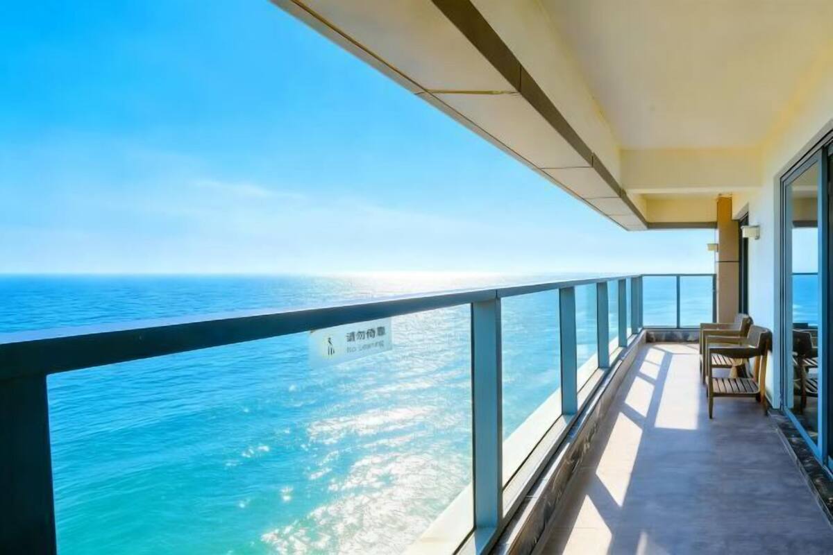 Un balcon avec vue sur la mer, un panneau indiquant un espace réservé aux fumeurs, et un coin salon avec une table et des chaises.