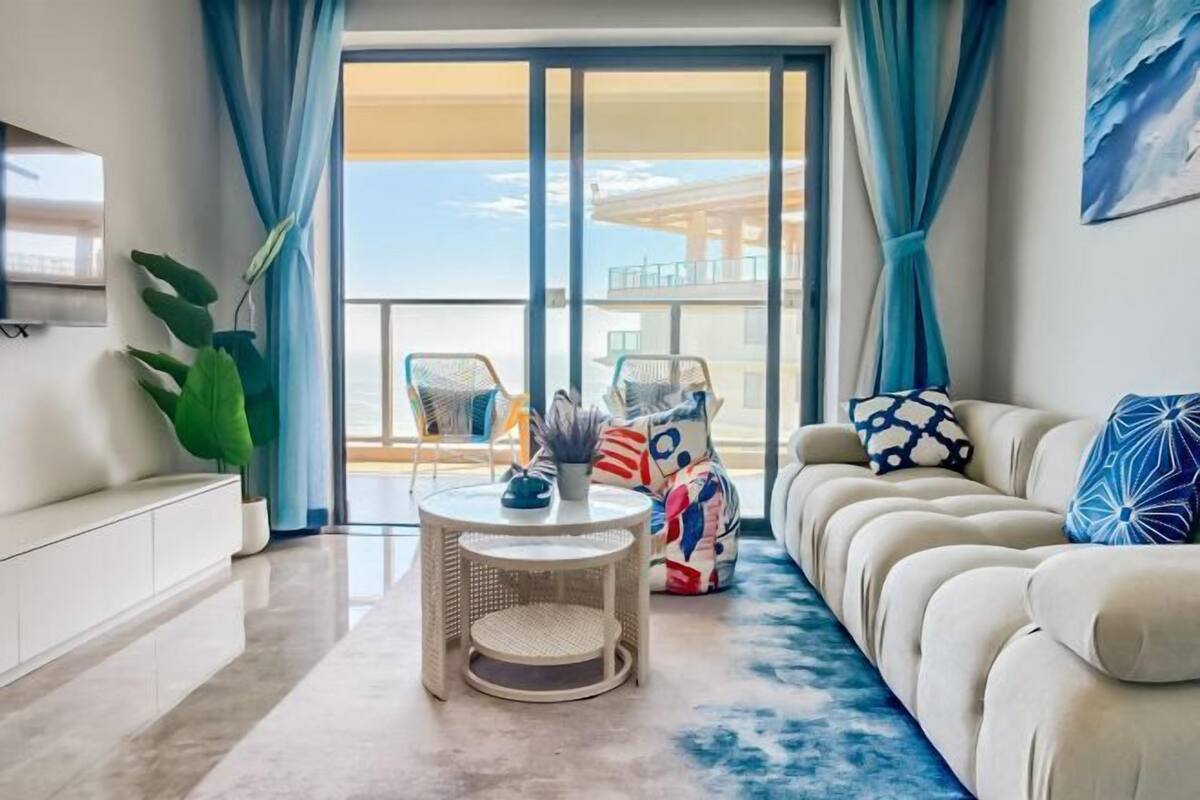 Un salon moderne avec un canapé, une table basse ronde et un balcon offrant une vue agréable.