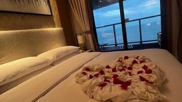 A hotel room with a bed, a view of the sea, and a large window.