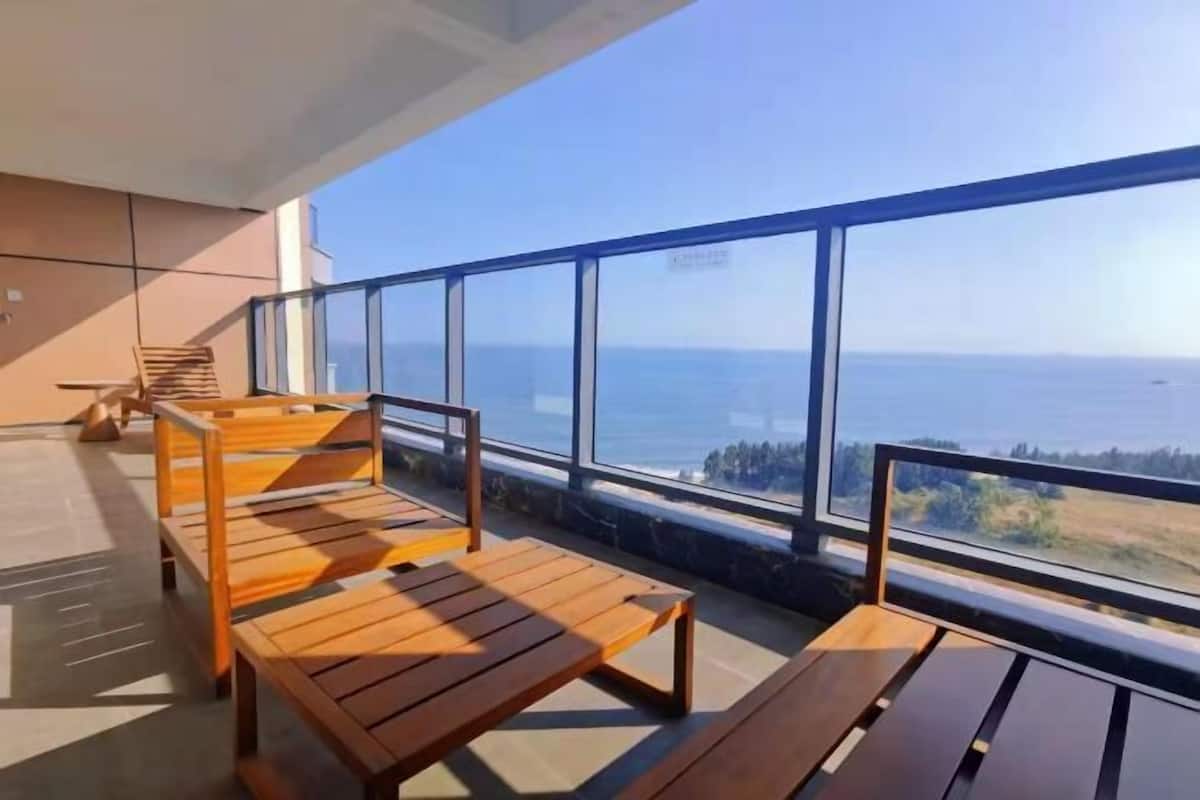 Un balcon doté de mobilier en bois et offrant une vue sur la mer.