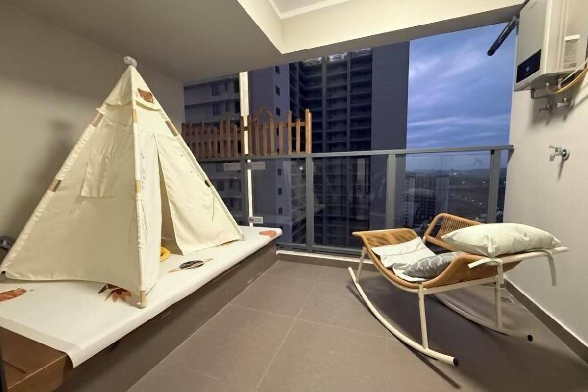 Un balcon avec une tente, un fauteuil à bascule et une vue sur le paysage urbain.