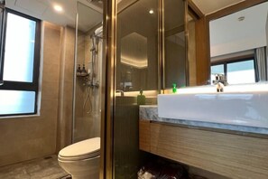 Et moderne badeværelse med bruseniche, toilet og et vaskeskab med spejl.