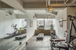 Une salle de sport Ă©quipĂ©e de matĂ©riel dâexercice, dâun tapis de course, dâun vĂ©lo dâappartement et dâun banc de musculation.