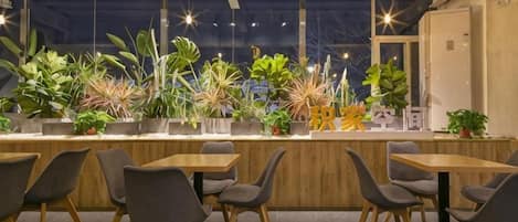 A modern interior with a long counter, multiple chairs, and potted plants.