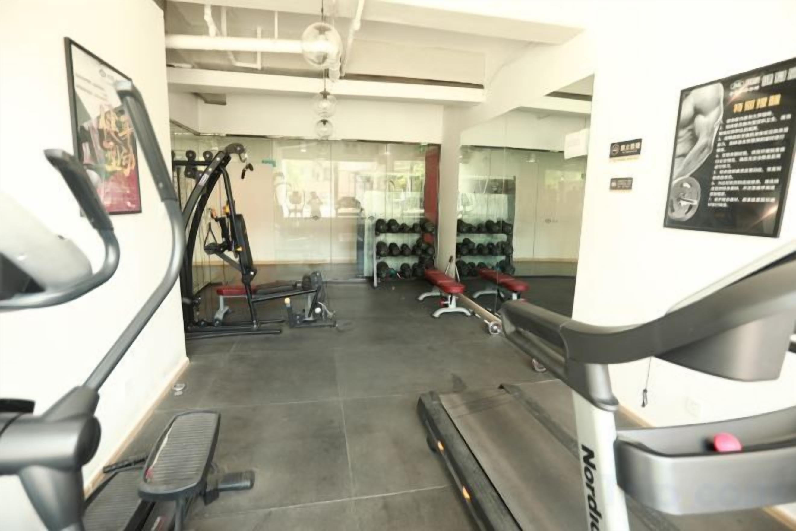 A gym with cardio machines, weightlifting equipment, and a mirror.