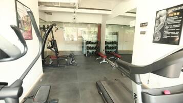 A gym with cardio machines, weightlifting equipment, and a mirror.