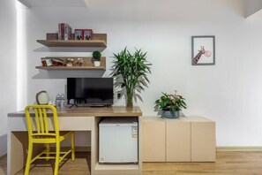 A compact living space with a kitchenette, a TV, a small fridge, a yellow chair, and a potted plant. - Product family selection Hotel (Zhengzhou)