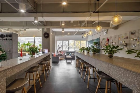 Un espace bar moderne doté d’un long comptoir, de nombreux tabourets et de luminaires suspendus.