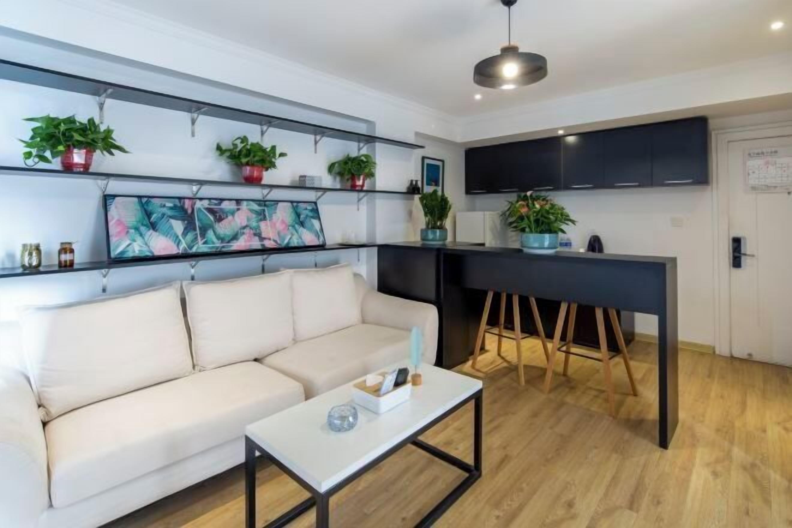 Una sala moderna con un sofá, una mesa de centro y una zona de cocina con encimera y armarios.