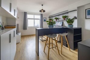 A modern kitchen with wooden flooring, a dark countertop, and two bar stools. - Product family selection Hotel (Zhengzhou)