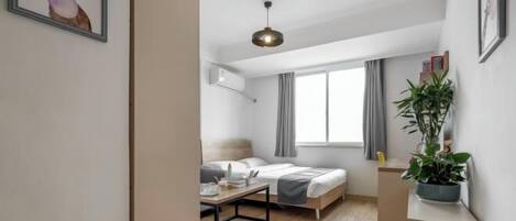 A modern hotel room with a bed, bedside table, and a potted plant.