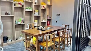 Een eethoek met een houten tafel en stoelen, omringd door planken met verschillende spullen.