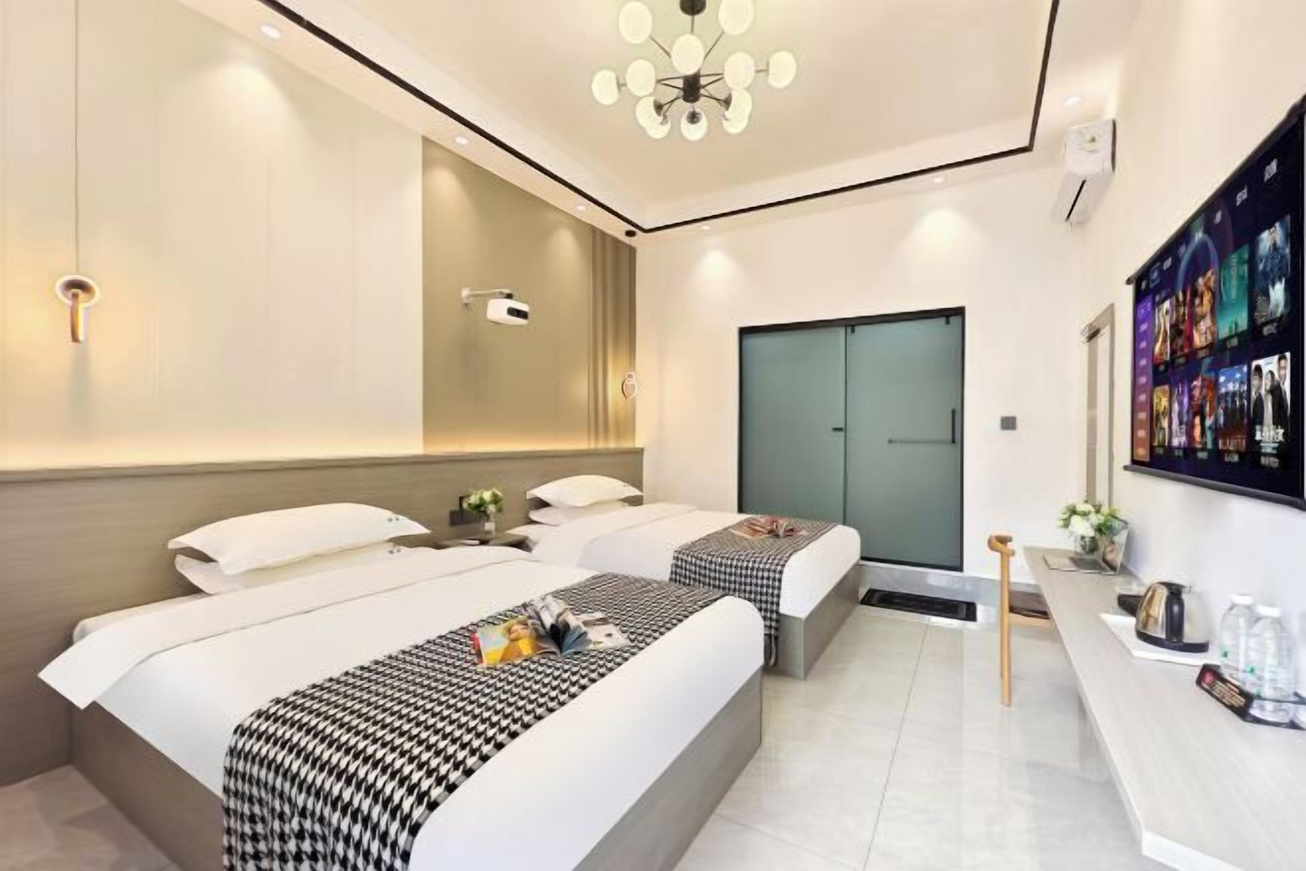 A modern hotel room with two beds, a desk, a shower, and a wall-mounted TV.