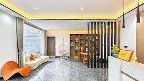 Een moderne hotel lobby met een receptiebalie, een zithoek en een decoratieve plant.