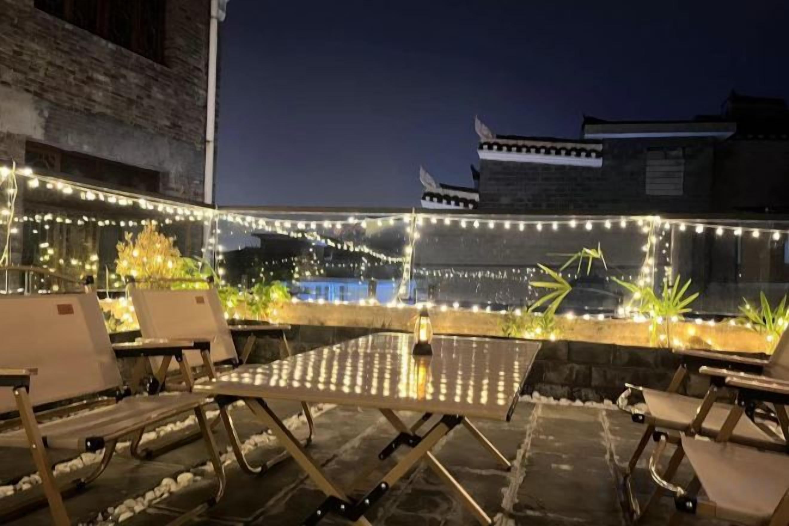 Eine Terrasse im Freien mit Lichterketten, einem Tisch und Loungemöbeln.