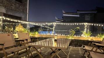 Eine Terrasse im Freien mit Lichterketten, einem Tisch und Loungemöbeln.