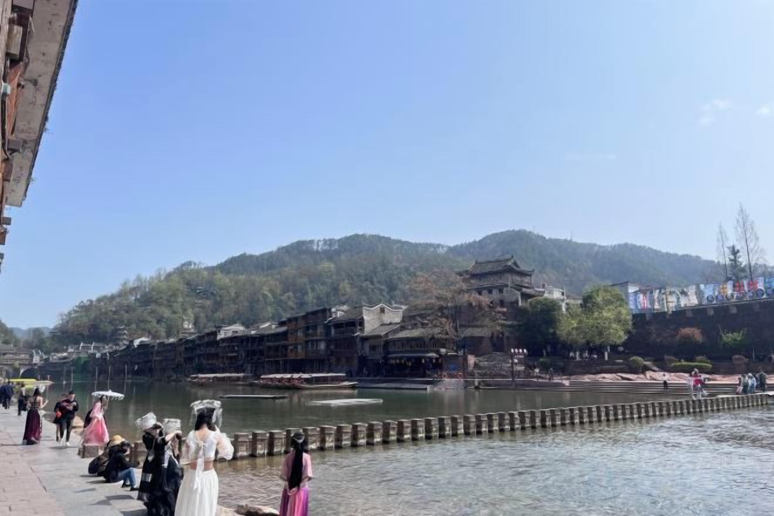 Una passeggiata lungo il fiume con edifici tradizionali e un molo in legno.
