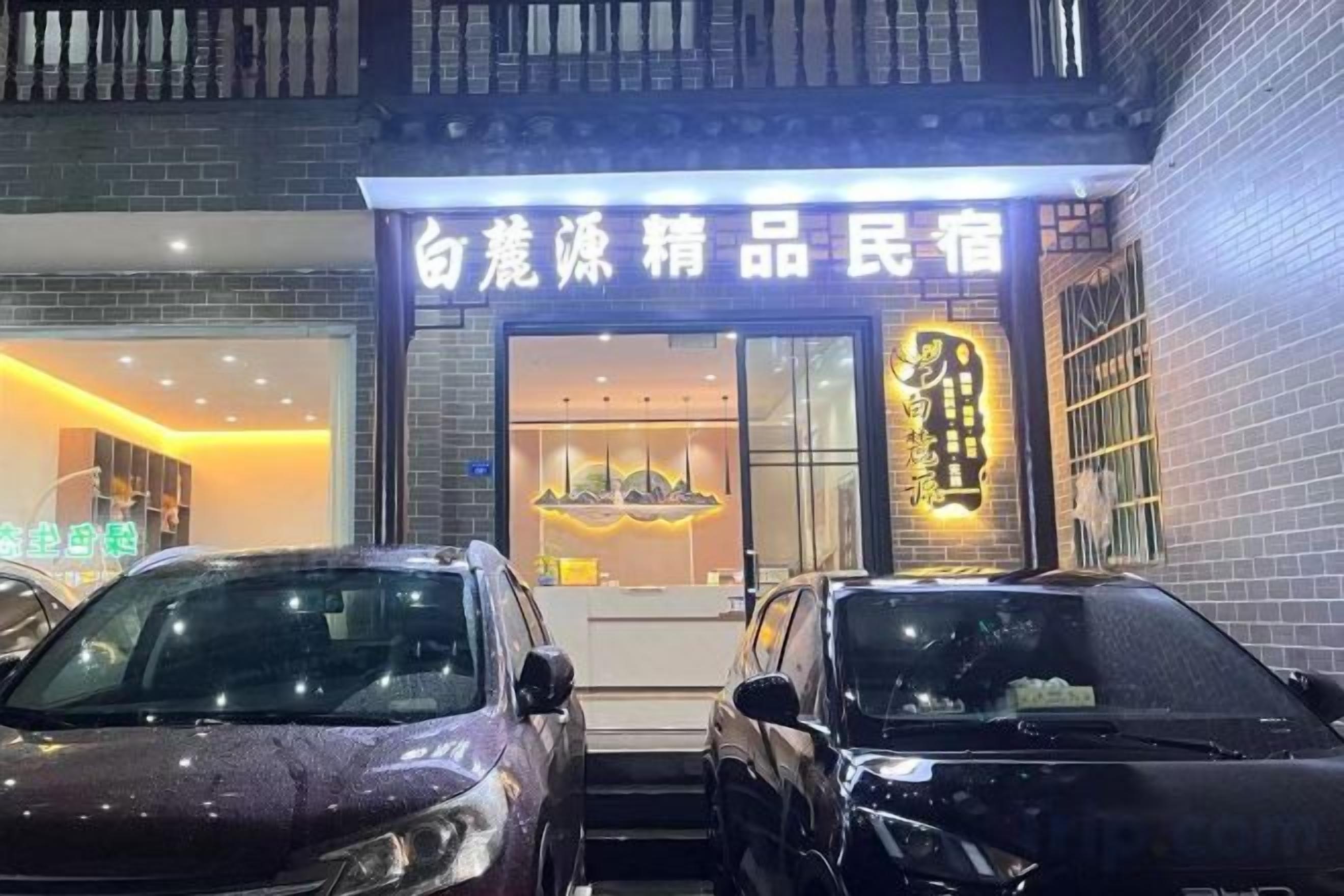 Ein Gebäude mit Schaufenster und zwei parkenden Autos davor.