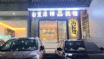 Ein Gebäude mit Schaufenster und zwei parkenden Autos davor.