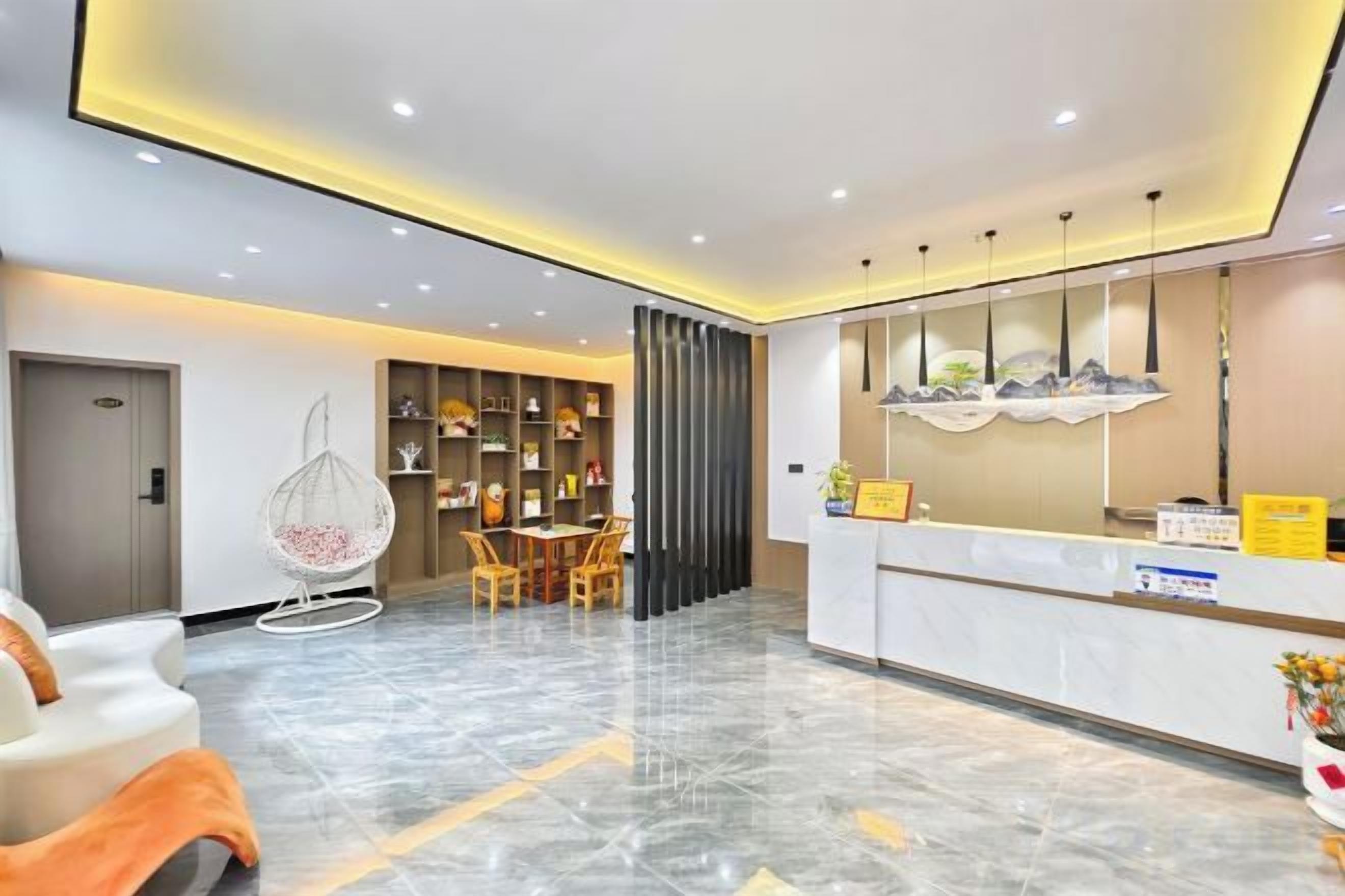 Zona de recepción de hotel con piso de mármol, mostrador de recepción, área de asientos con sillas y una pared decorativa.