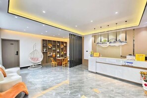 A hotel reception area with a marble floor, a reception desk, a seating area with chairs, and a decorative wall. - Bailuyuan Boutique Homestay (Fenghuang County)