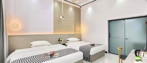 A modern hotel room with two beds, a desk, and a wardrobe.