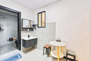 A modern bathroom with a shower, a vanity with a mirror, and a small round table with stools. - Bailuyuan Boutique Homestay (Fenghuang County)