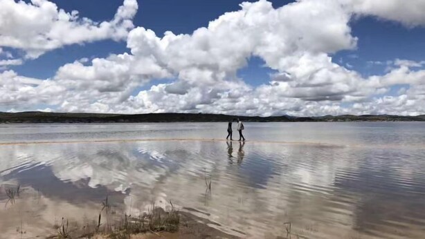 Un lago amplio y tranquilo con cielo despejado y algunas nubes.