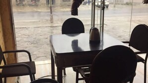 Una mesa y sillas dentro de un edificio, con vista a la calle.