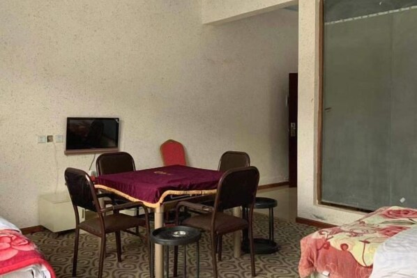 A room with a bed, a table with chairs, a television, and a sliding door. - HaiziMountainGrandHotel (Daocheng County)