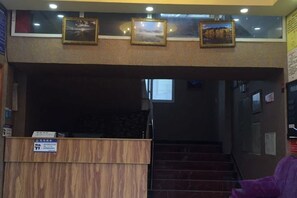 Un área de recepción con un escritorio de madera, una escalera y cuadros en la pared.
